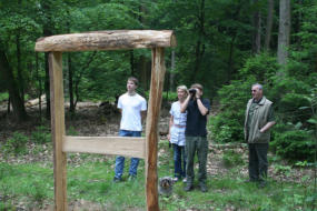 Menschen stehen vor einem Holzrahmen im Wald